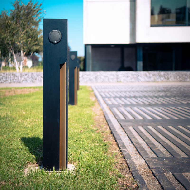 Two Veton charging stations on a lawn beside a modern building, socket outlet visible.